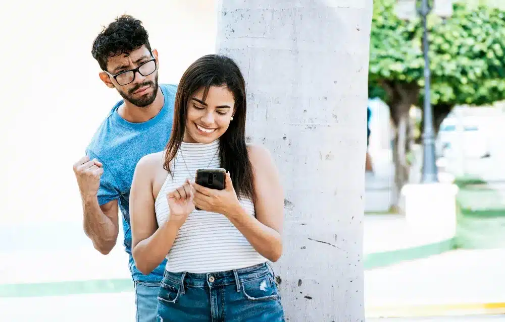 Pareja feliz compartiendo la pantalla del móvil en la calle