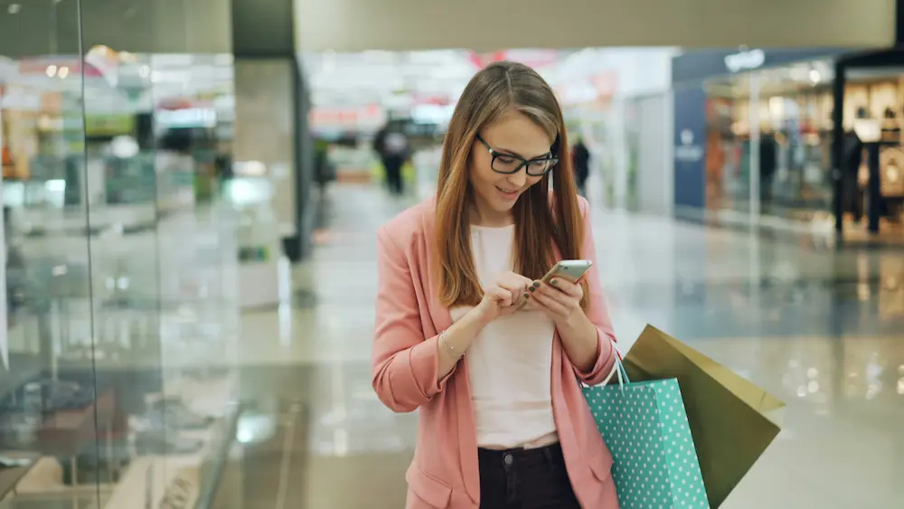 Mujer feliz usando el móvil para obtener préstamo rápido de 50 euros tras sus compras