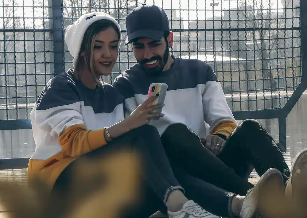 Pareja sonriente mirando el teléfono recibiendo préstamos de 800 euros al instante sin complicaciones